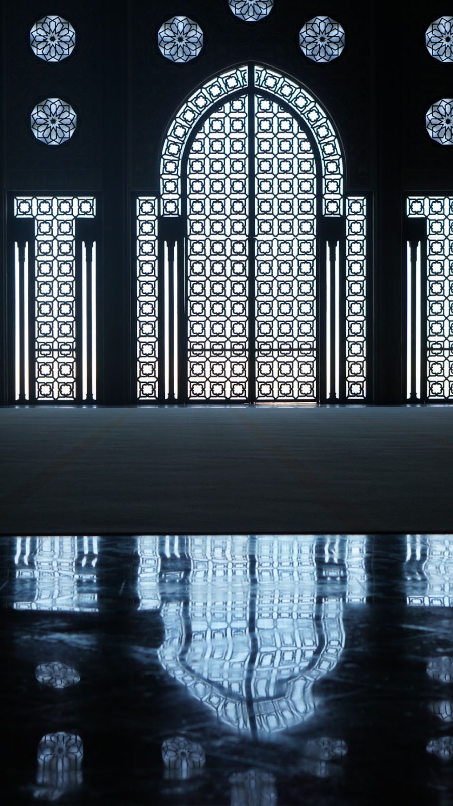 Ventanas talladas reflejadas en la Mezquita Hassan II