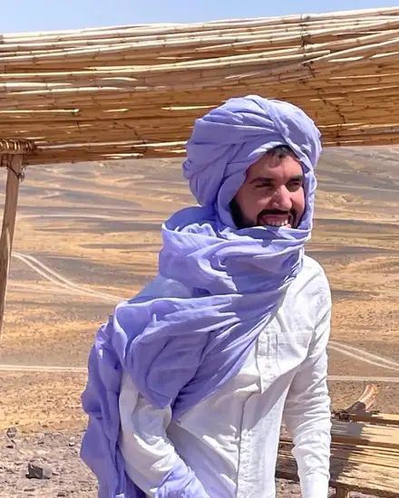 Mubarak, founder of Through Morocco, wearing a lavender turban in the desert