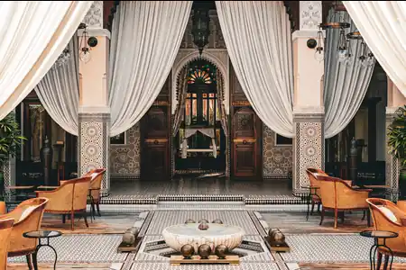 Tiled riad courtyard with a marble fountain and draped arches